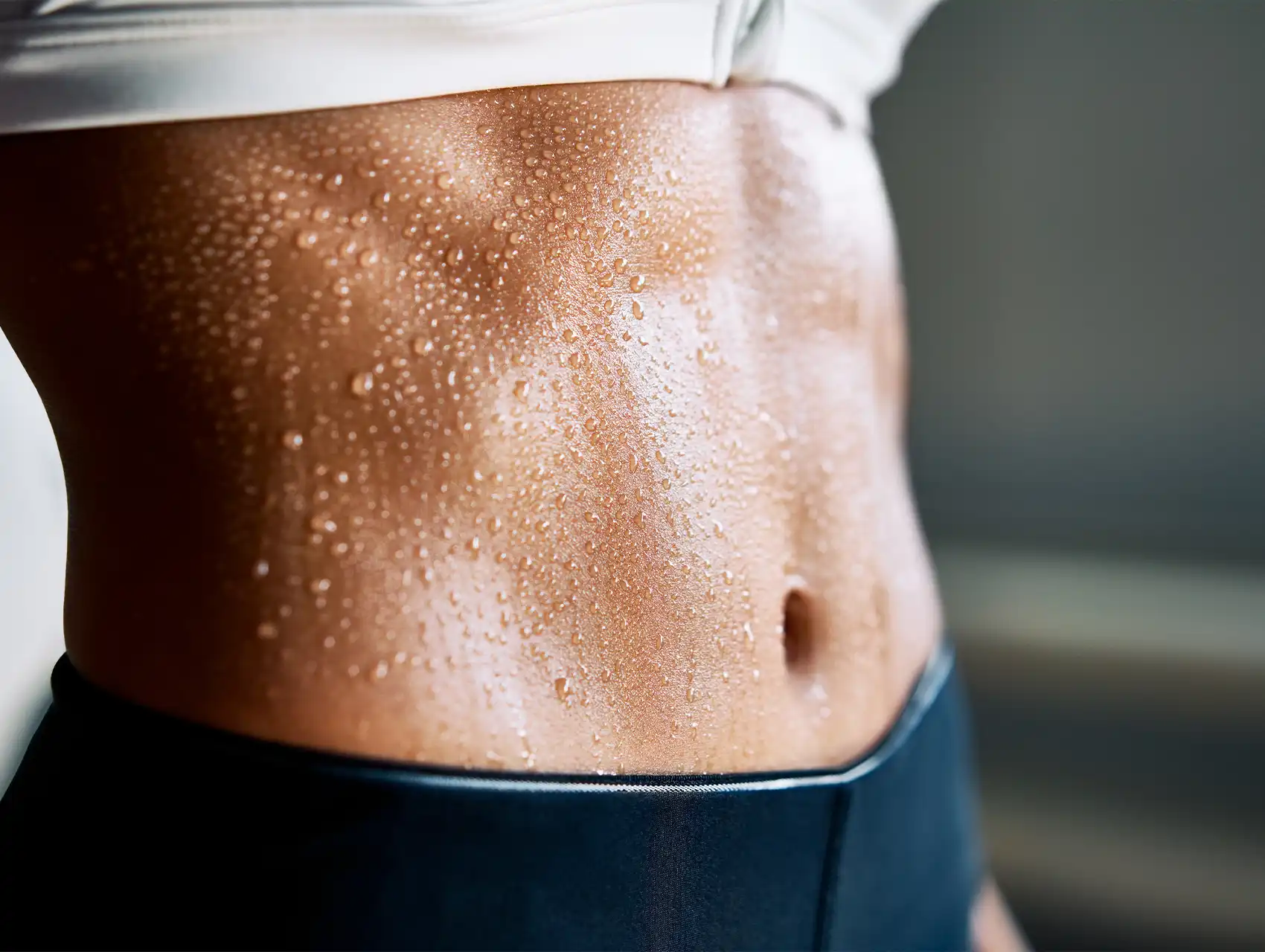 Close-up of a toned, sweaty abdomen after exercise, symbolizing body goals and the question: do waist trainers work.