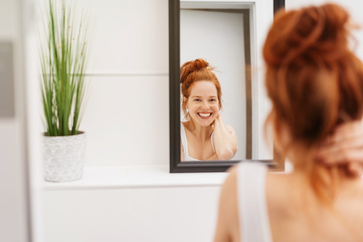 Woman Looking in Mirror and Smiling