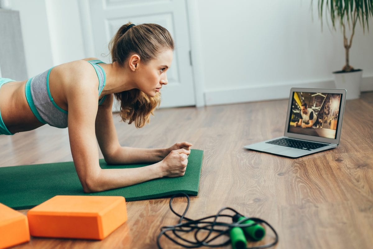 Woman doing plank while watching on laptop