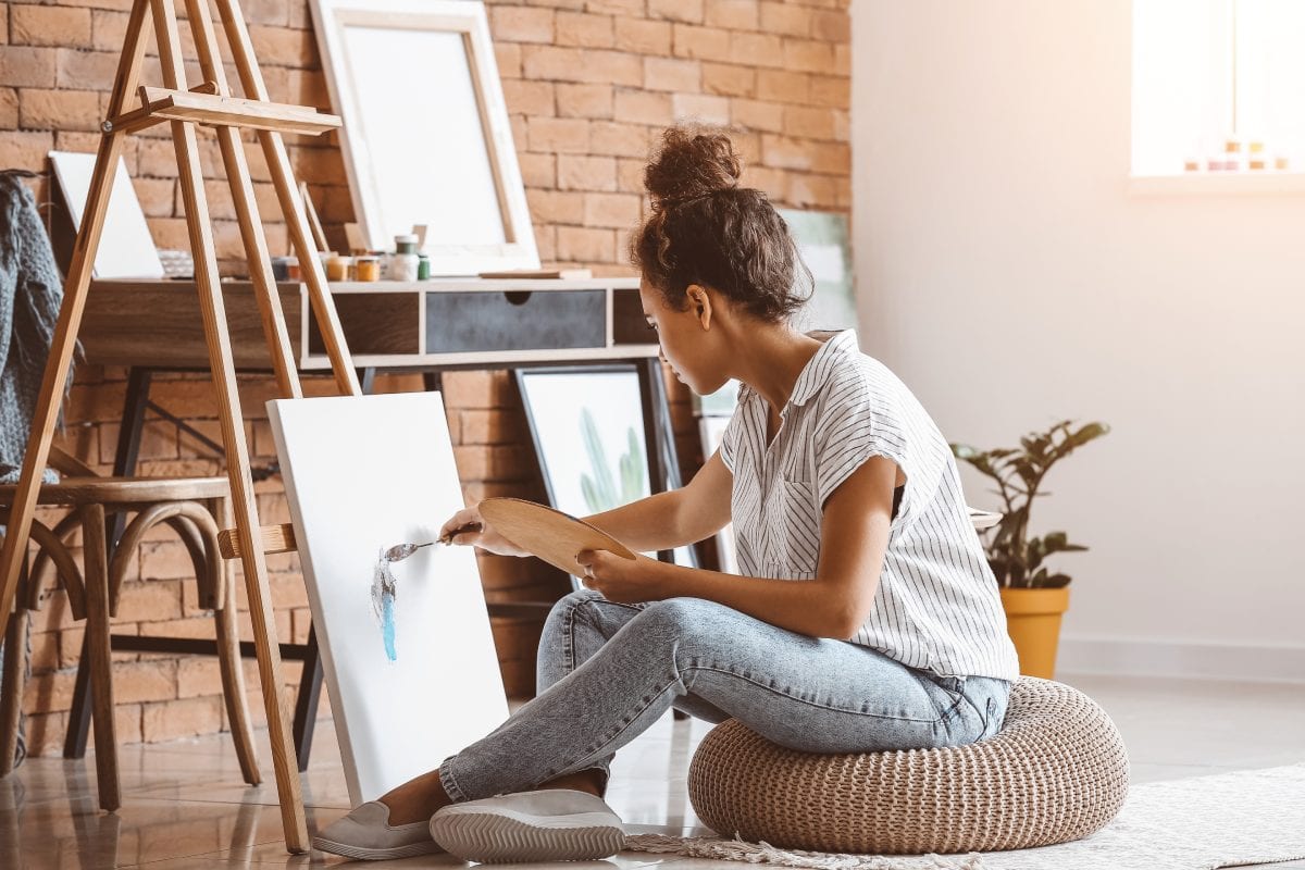 Young African-American woman painting in living room