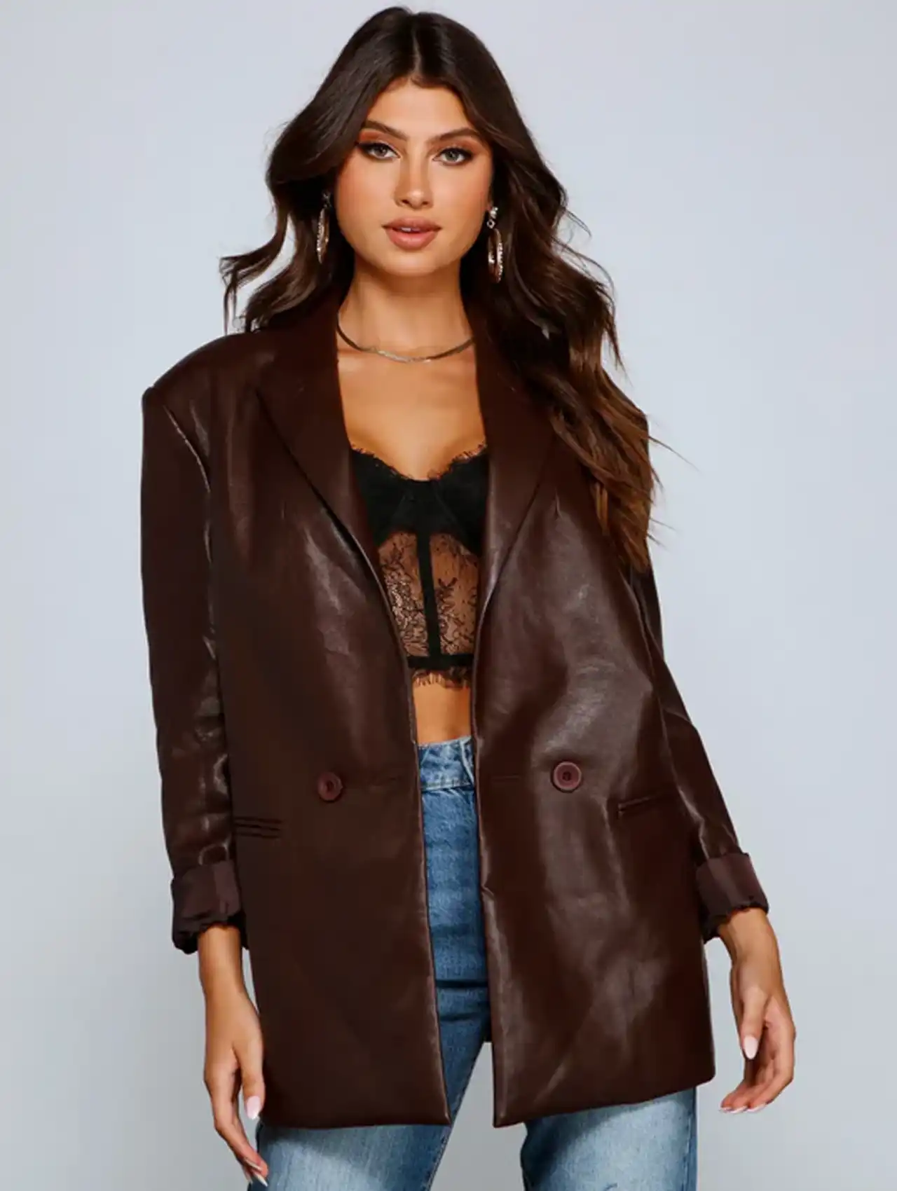 Woman wearing a brown leather blazer for women over a lace top and jeans.