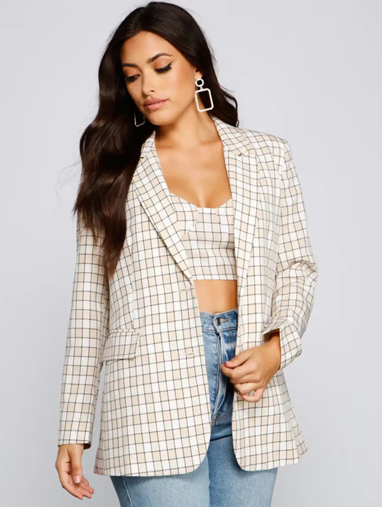 Woman wearing a plaid blazer for women styled with a matching crop top and jeans.