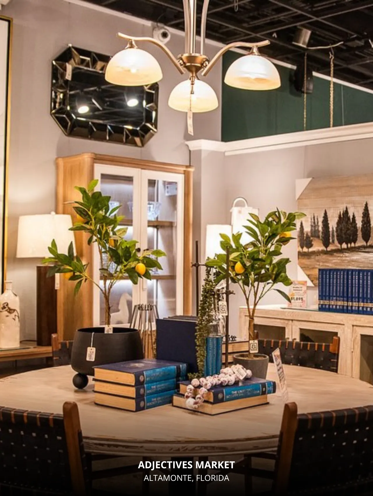 Adjectives Market Altamonte interior display featuring a round dining table styled with books, potted lemon trees, and curated home-décor accents.