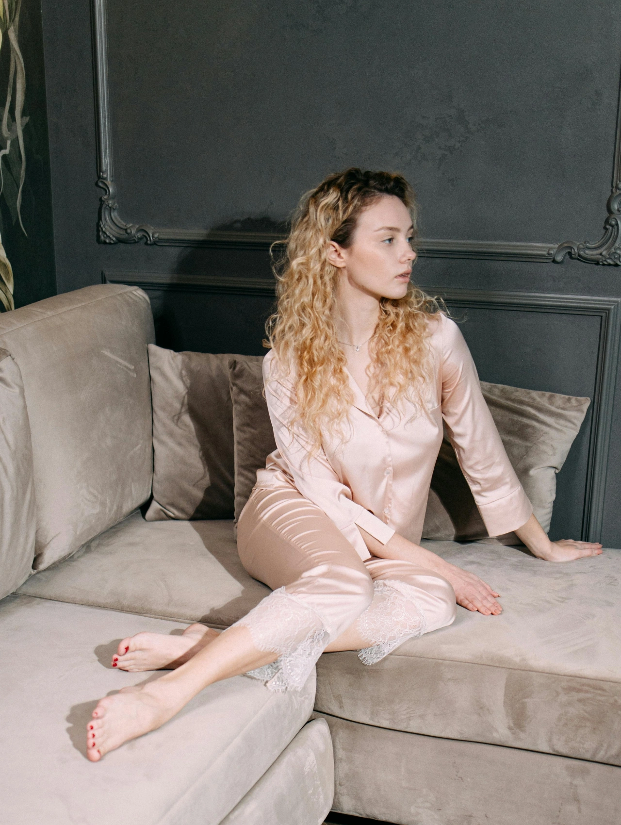Woman in silky cute sleepwear lounging on a couch, modeling soft satin pajamas with lace details for a cozy yet elegant look.