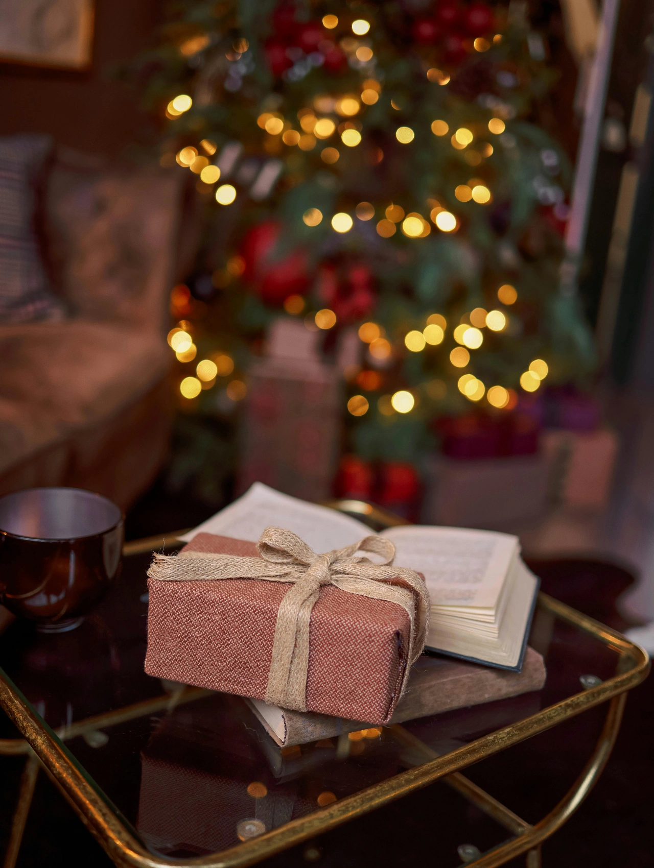 Cozy holiday setting with a wrapped present and an open book on a table, perfect for illustrating useful gifts.