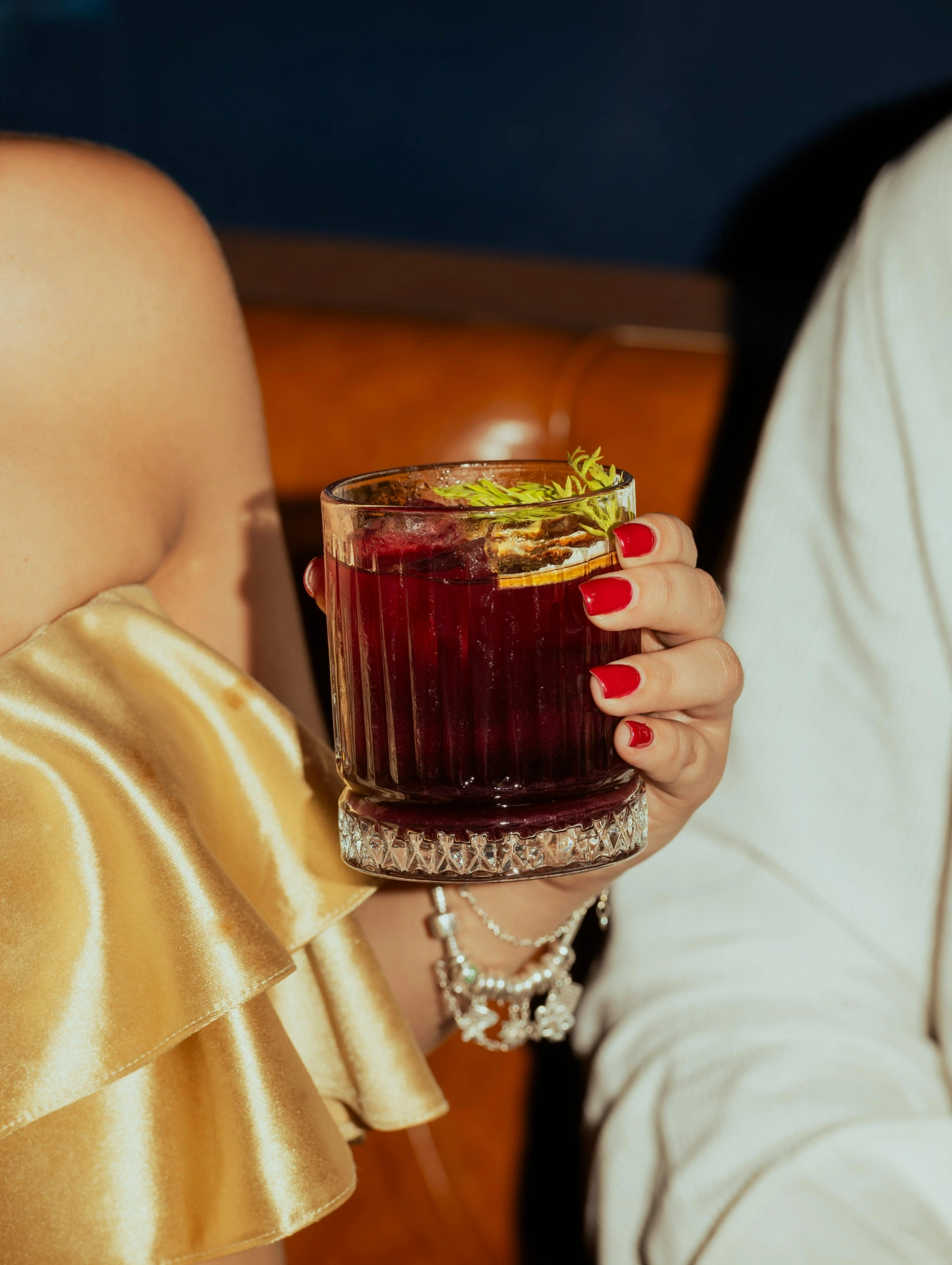 Hand holding a festive red cocktail glass, creative drink from Thanksgiving Party Ideas.