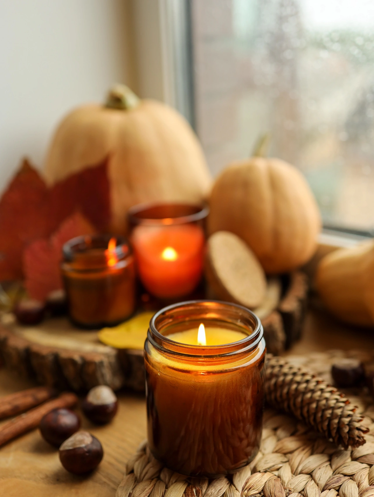 Warm candle and fall decor scene with pumpkins — cozy ambience for Thanksgiving Party Ideas.