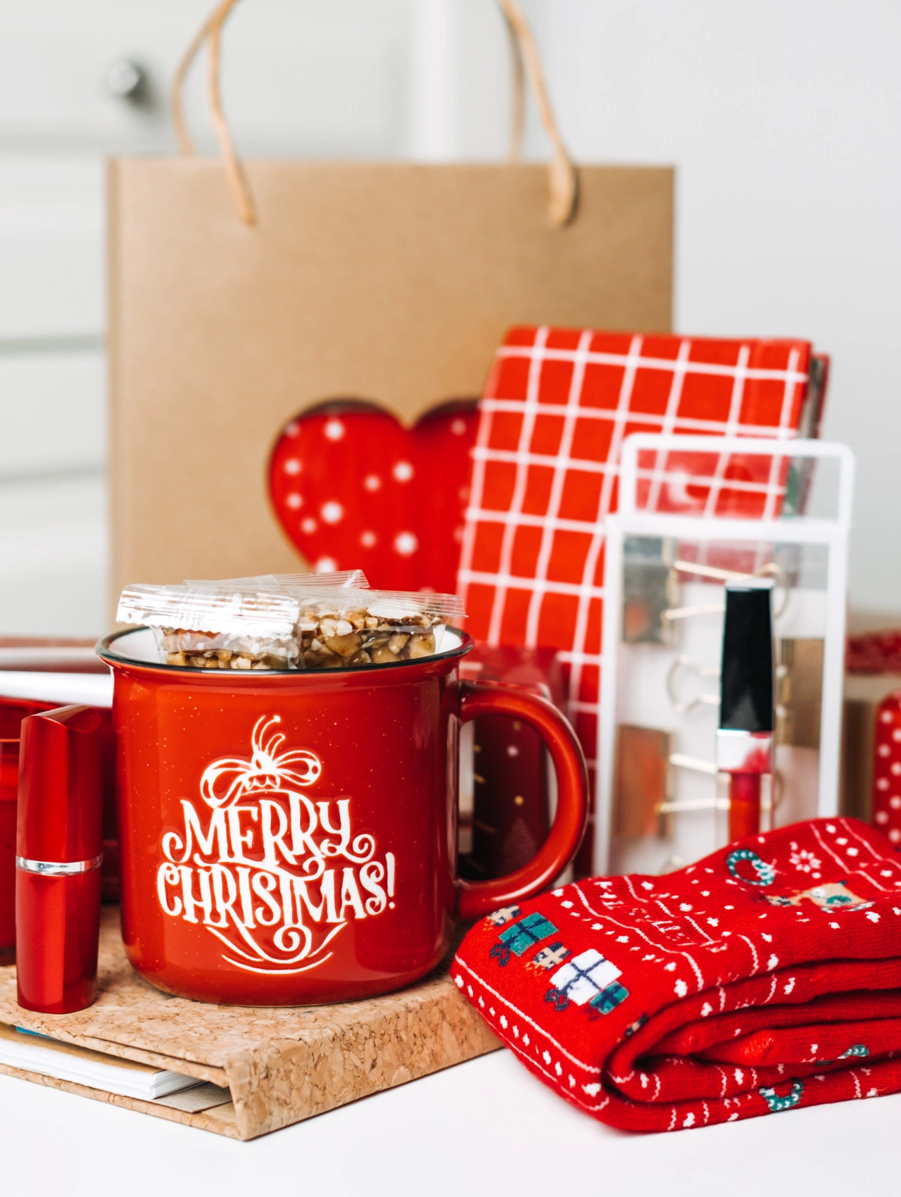 Festive holiday gift assortment with red Christmas mug, wrapped presents, and cozy socks, themed around gift sets for her