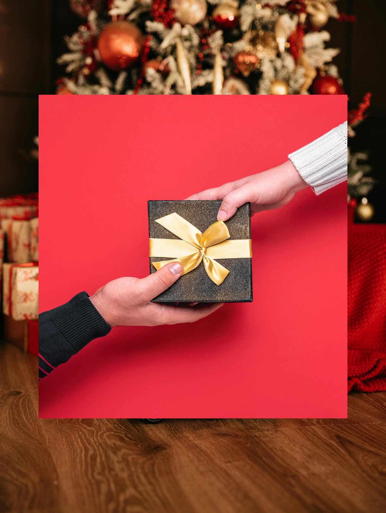 Hands exchanging a small gift box with a gold ribbon, representing thoughtful last minute Christmas gifts for mom.