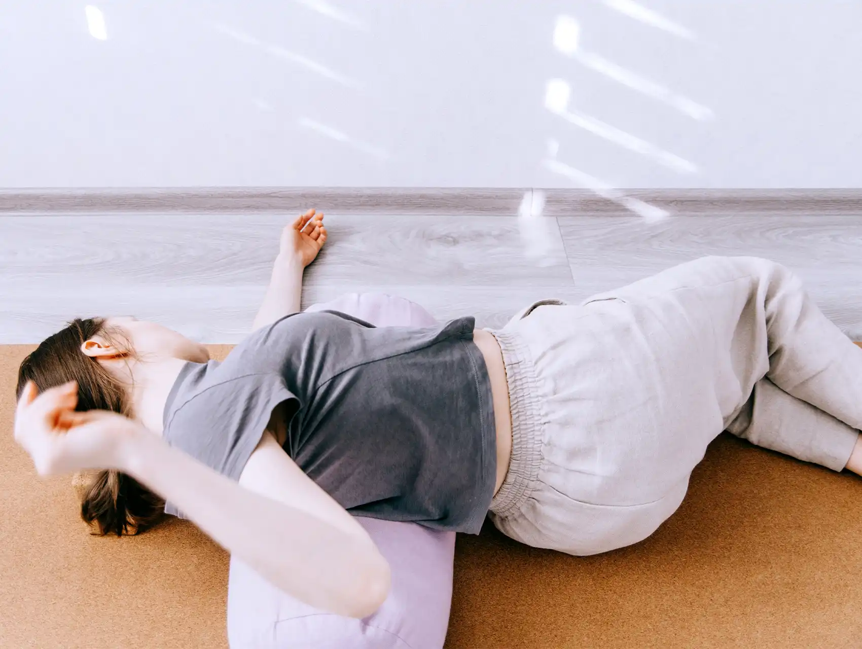 Woman in supported twist pose lying on lilac yoga bolster with bolsters
