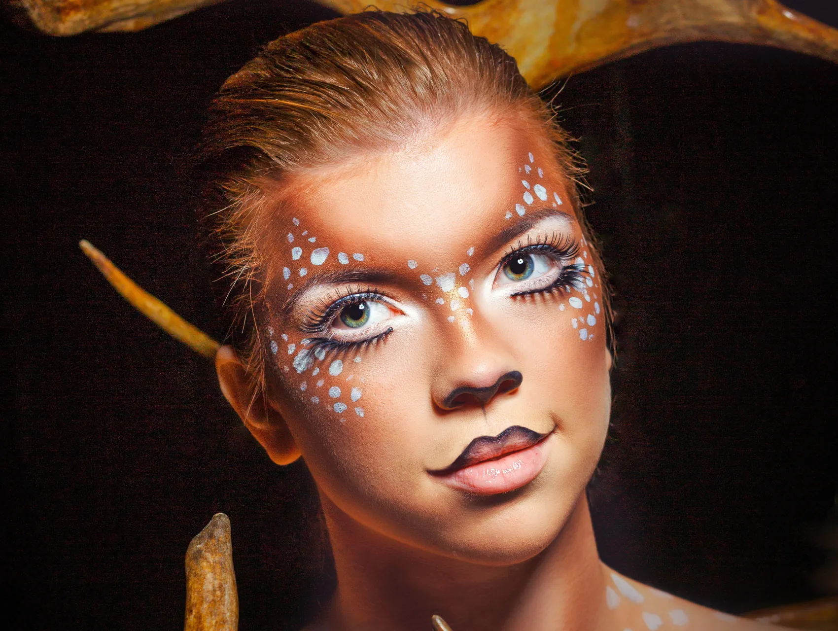 Deer Halloween makeup look with white freckle spots, soft brown contour, black nose tip, and a half black upper lip