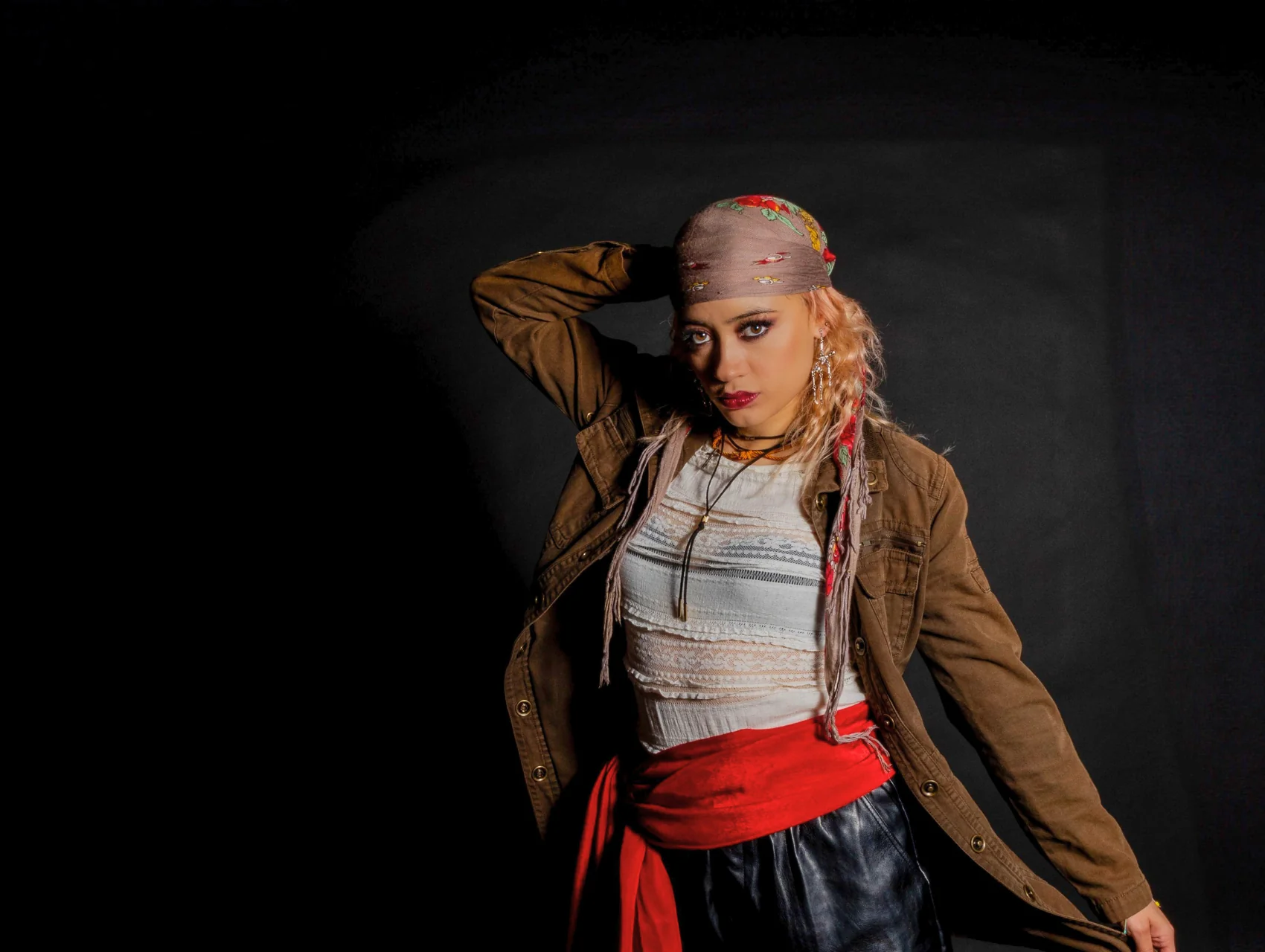 Pirate Halloween makeup look with smoky brown eyes, deep red lips, floral bandana, and a red sash over a white top