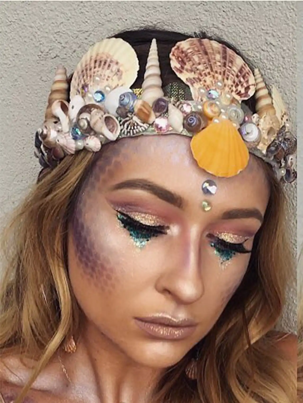 Mermaid-inspired halloween makeup looks with seashell crown, glitter tears, and shimmery scales.