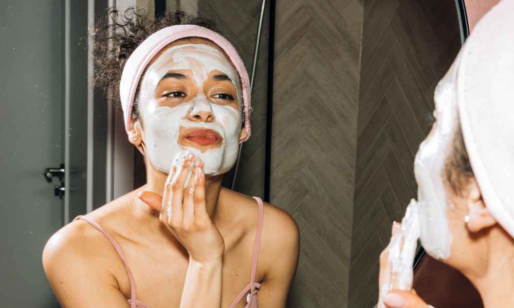Girl doing a face mask in front of mirror