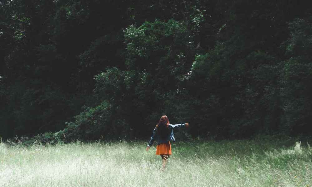 Woman walking around an open field of grass and nature