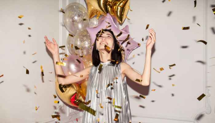 Woman dancing in confetti on her silver new year's dress