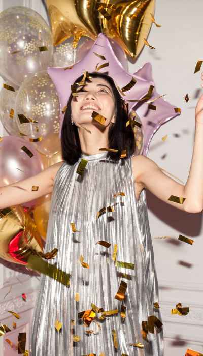 Woman dancing in confetti on her silver new year's dress