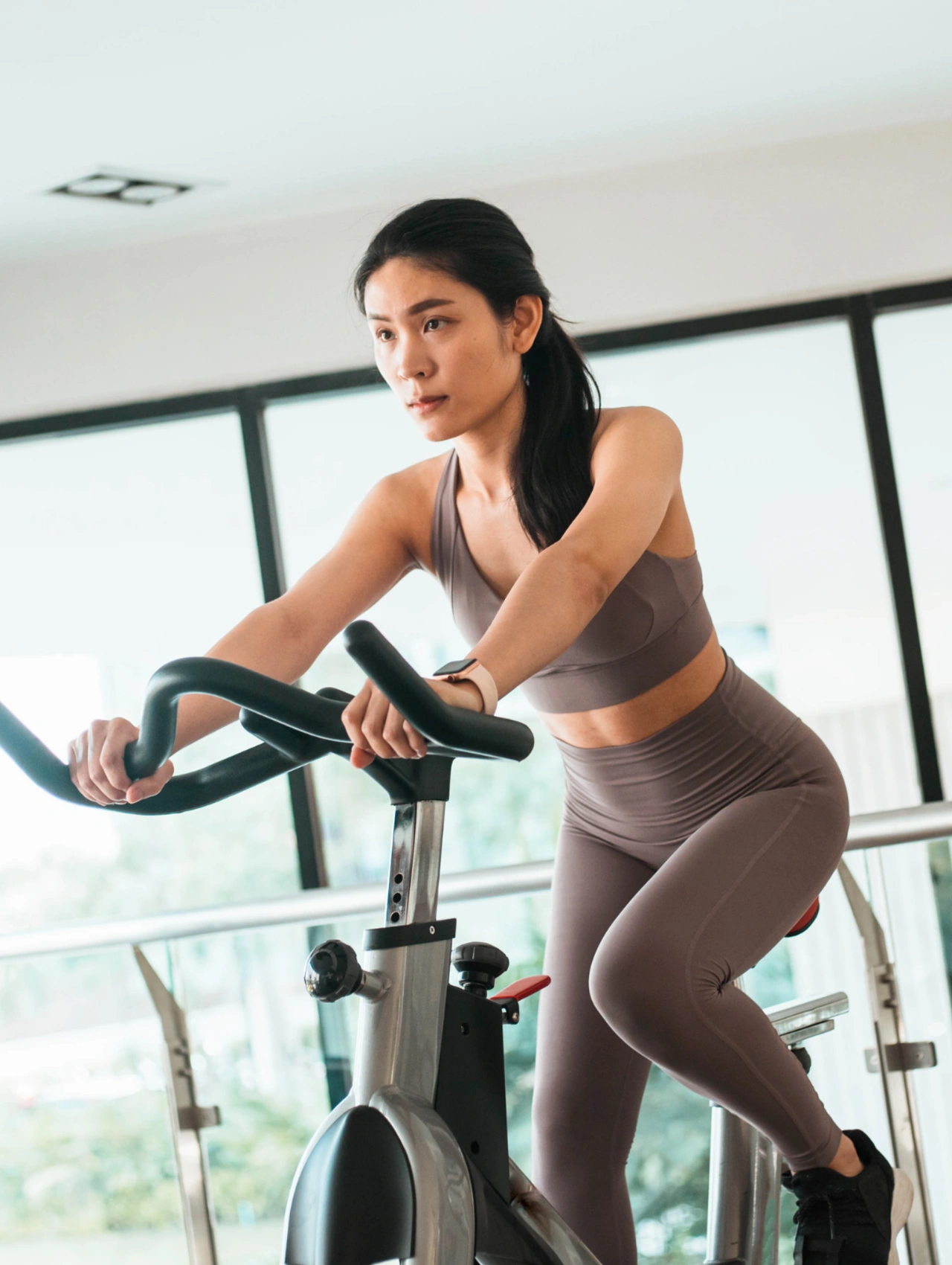 Woman using a stationary bike indoors, a cardio-focused gym essential for beginners.