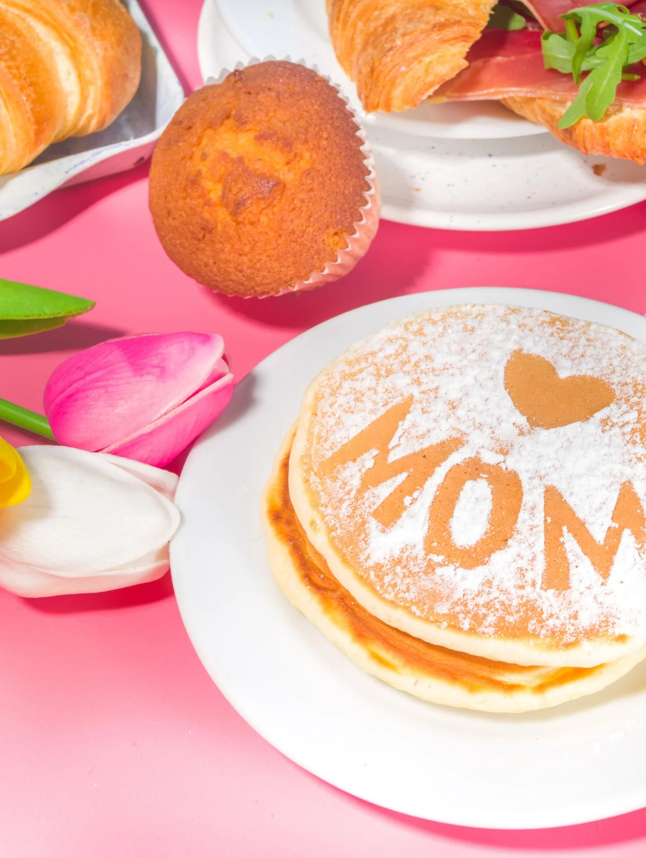 Pancakes dusted with powdered sugar spelling MOM next to tulips and pastries, perfect brunch inspiration for things to do in Orlando for Mother's Day