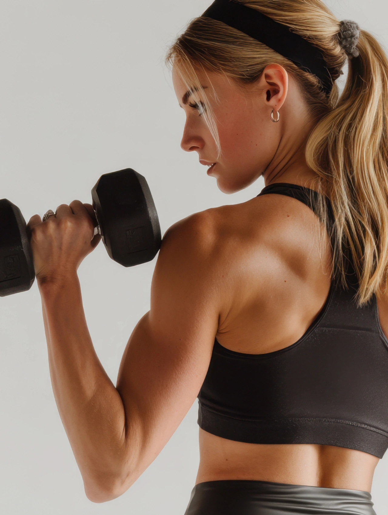 Woman lifting dumbbells, highlighting free weights as gym essentials for beginners.