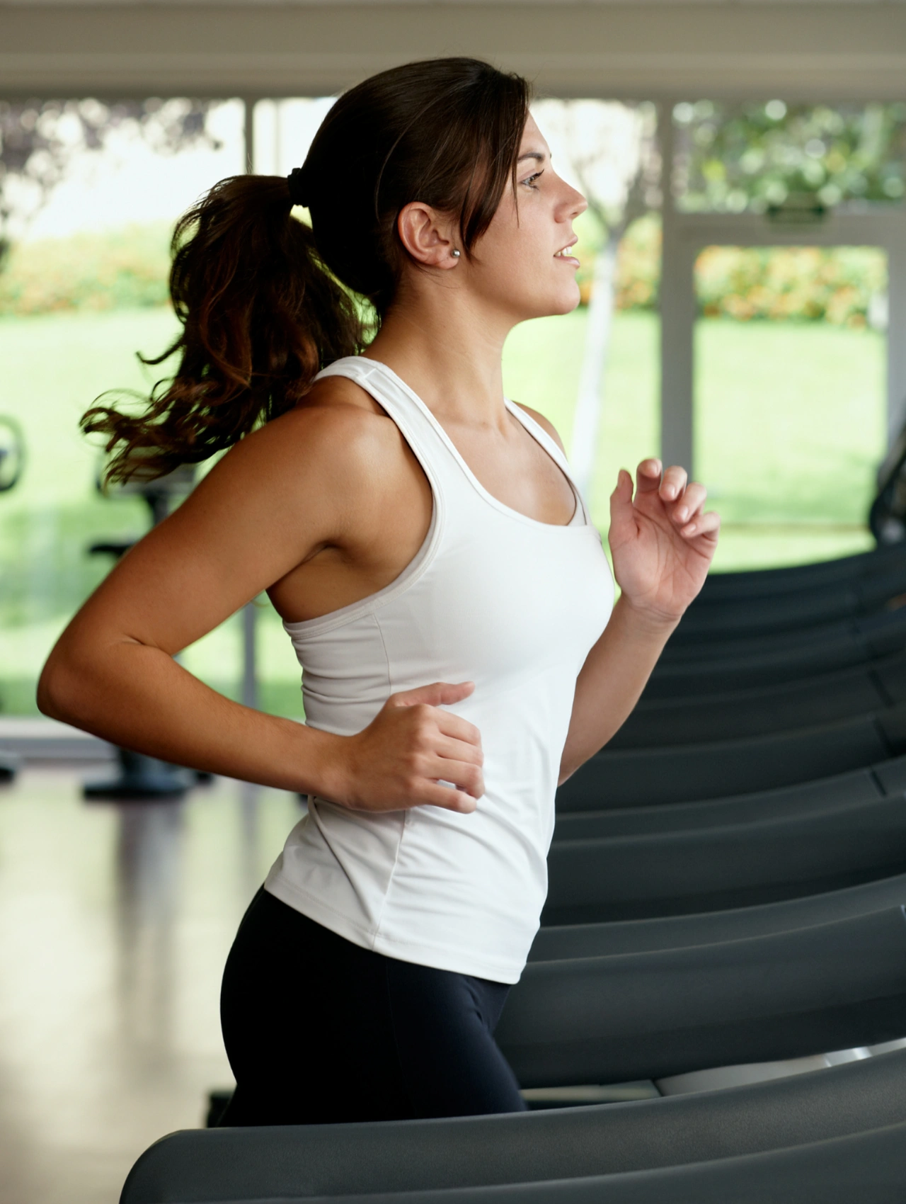 Treadmill workout, woman jogging indoors, gym essentials for beginners starting with cardio training.