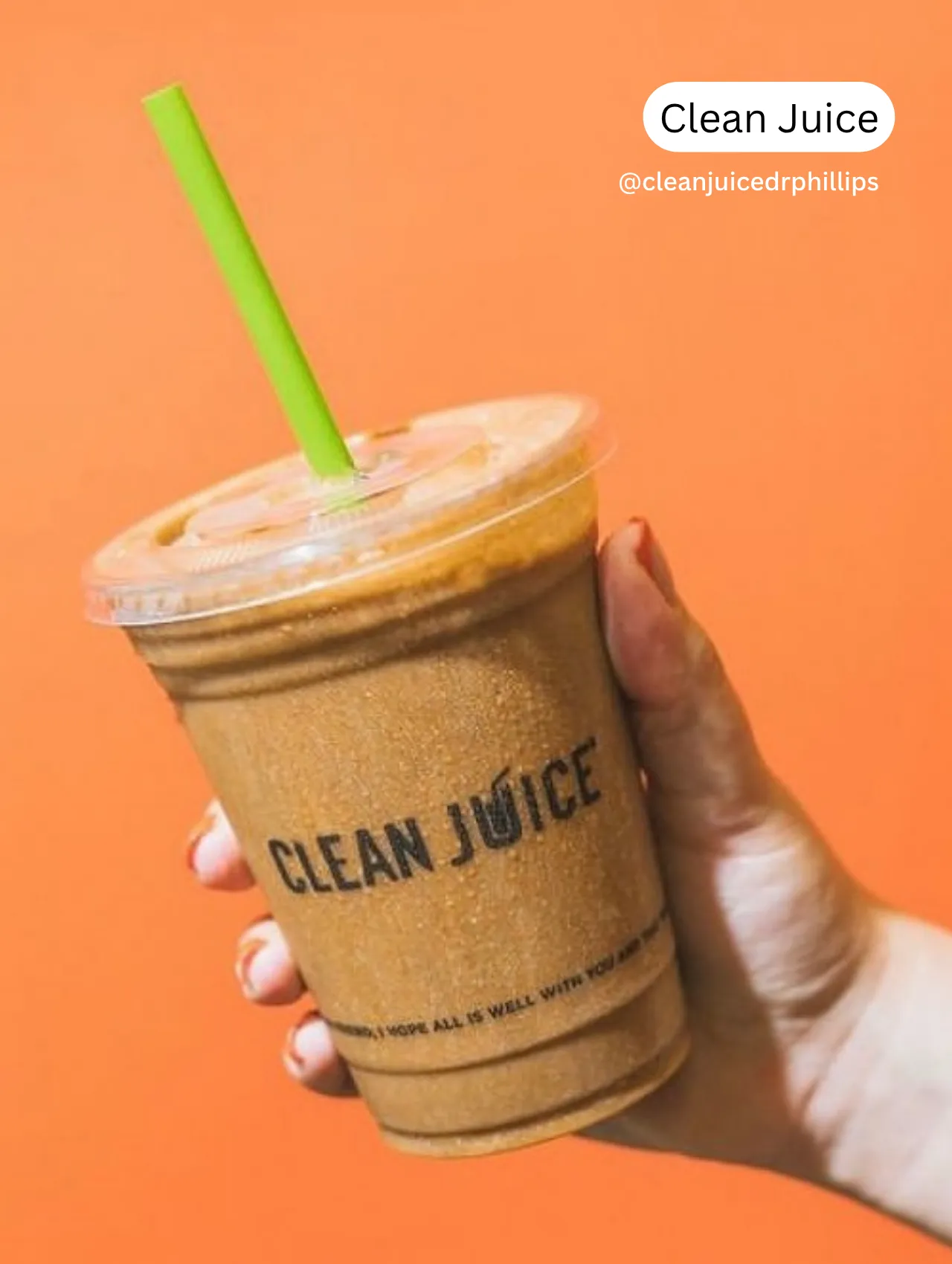 Clean JuiceSmoothies in Orlando – hand holding a cold smoothie from Clean Juice against a bright orange background, representing healthy and refreshing drink options in Orlando.