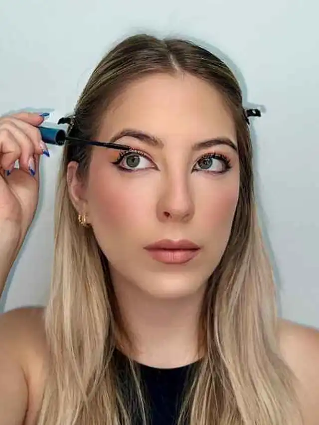 a woman applying mascara on her eye