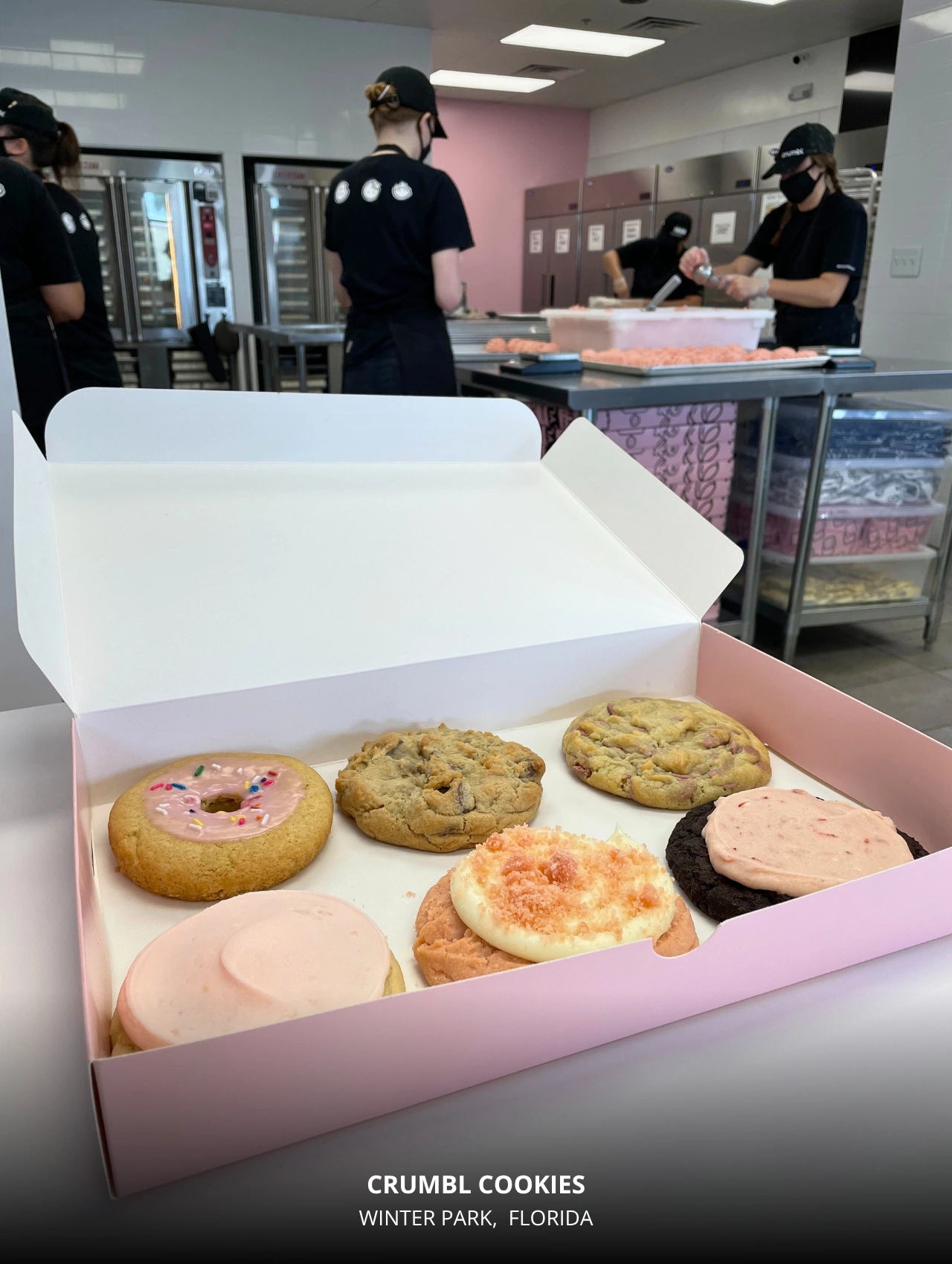 Open pink box filled with six assorted cookies inside Crumbl Cookies Orlando kitchen