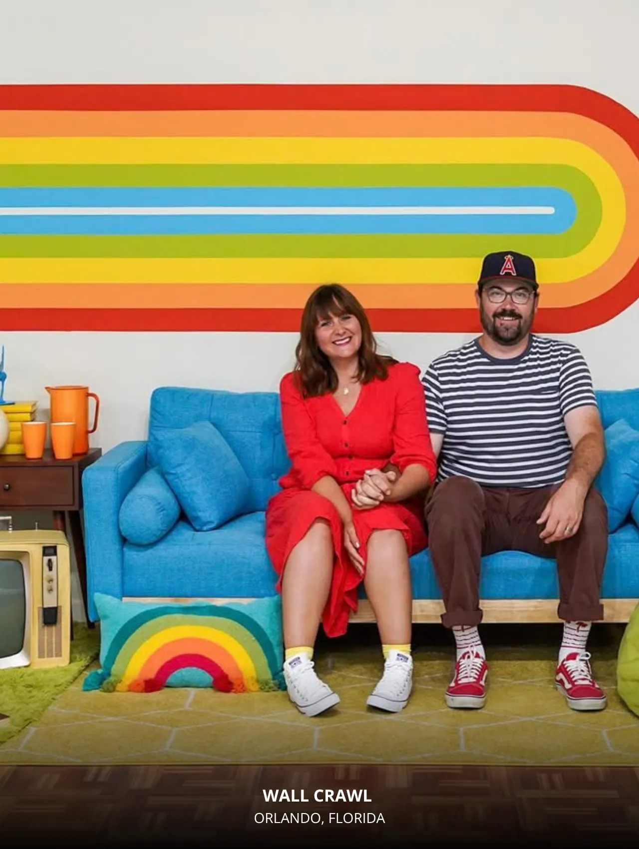 Couple posing on a retro blue couch in the rainbow set at Wall Crawl Orlando – Top Locations in Orlando to Take Beautiful Photos for Your Instagram.
