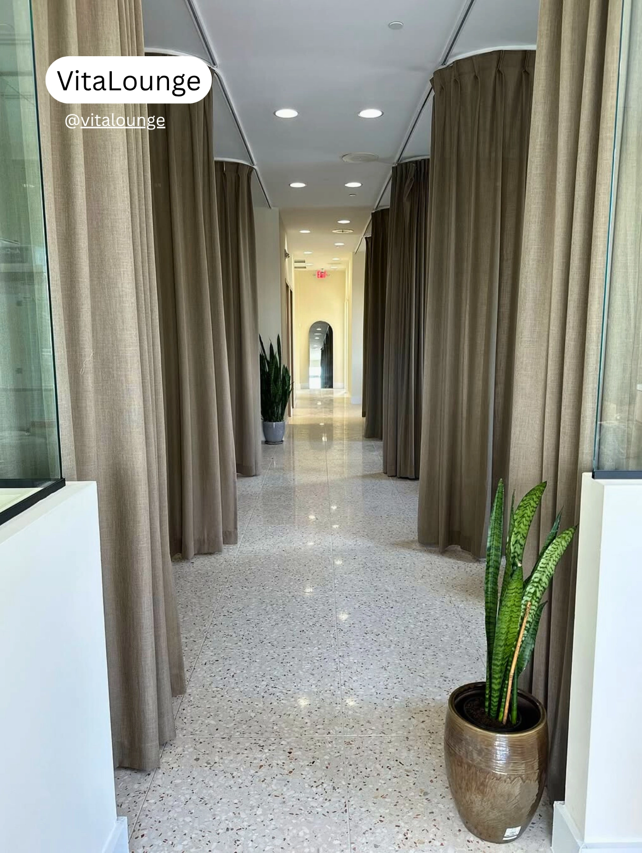 Interior hallway of VitaLounge in Orlando with privacy-curtained wellness treatment rooms and minimalist decor.