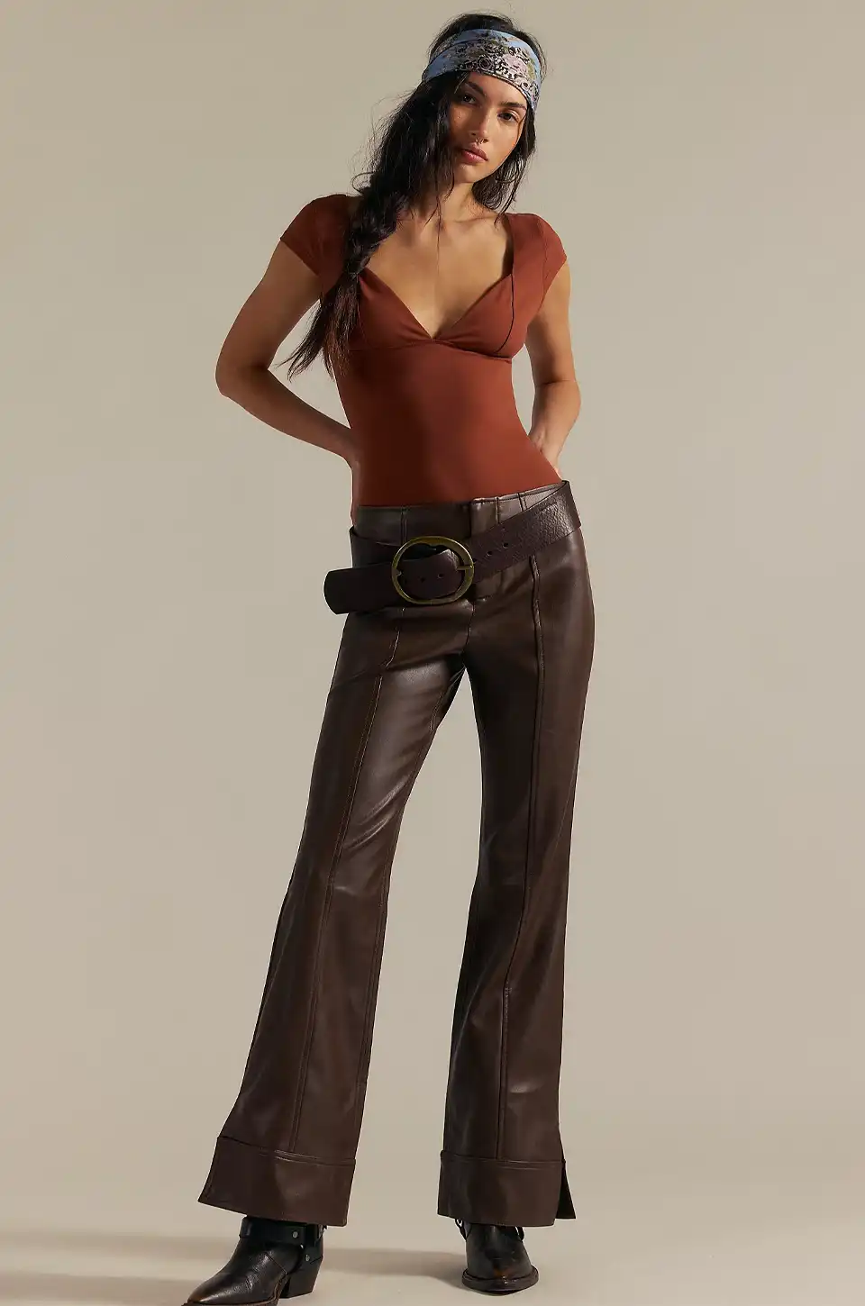 Model wearing brown faux leather pants with a fitted top and wide belt.