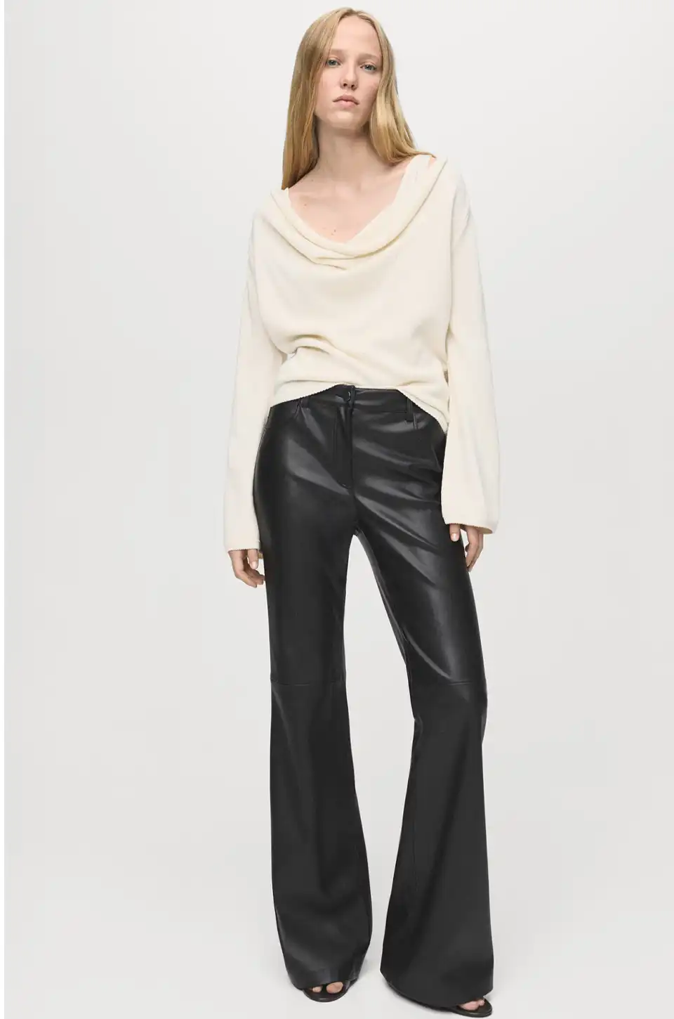 Model wearing wide-leg faux leather pants with a white sweater and open-toe heels.