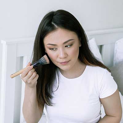 Woman applying complexion products on her face.