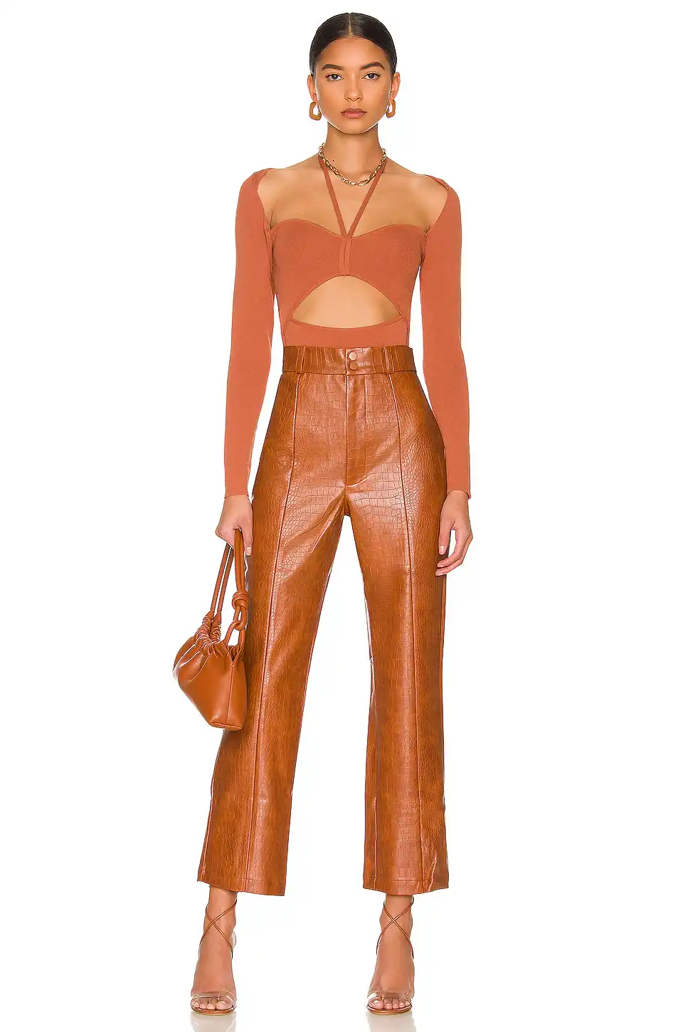 Woman wearing high-waisted cognac faux leather croc-textured pants with strappy heels and a cutout top.