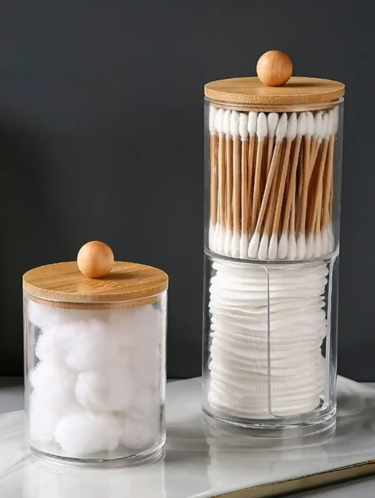 Frascos de vidrio con tapa de madera para algodón y hisopos en tocador de maquillaje.