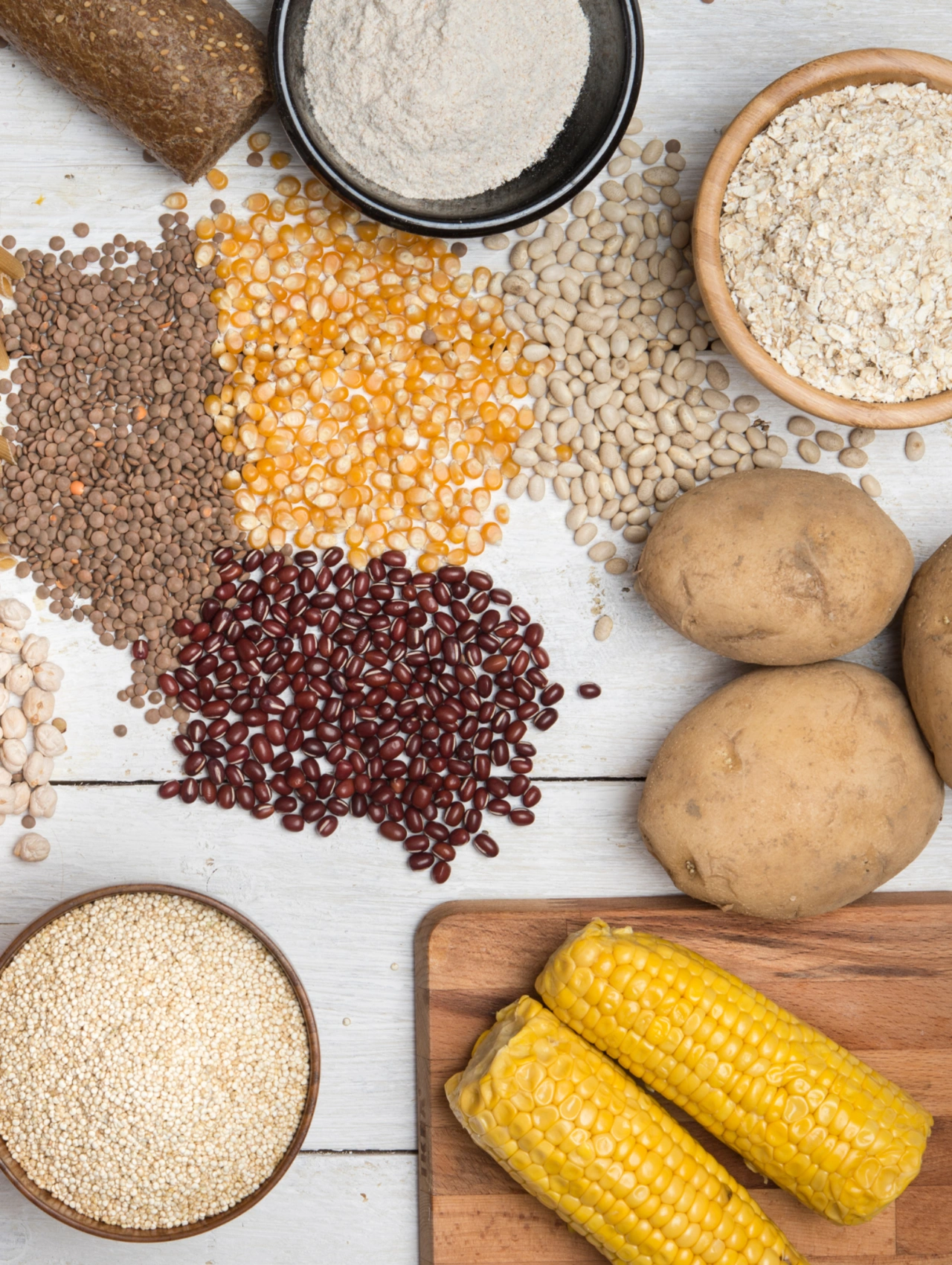Weight loss detox concept showing healthy carbohydrate sources like whole grains, legumes, corn, oats, and potatoes arranged on a rustic surface.