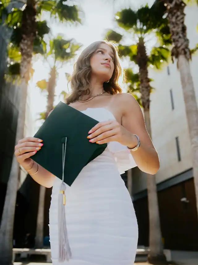 a woman in a white dress holding a graduation cap