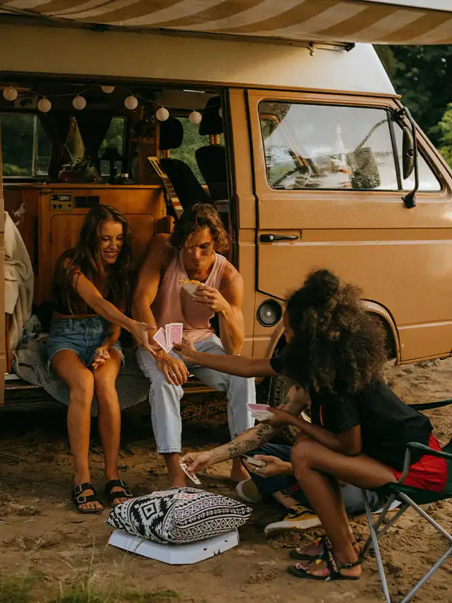 a group of people sitting in a van playing cards