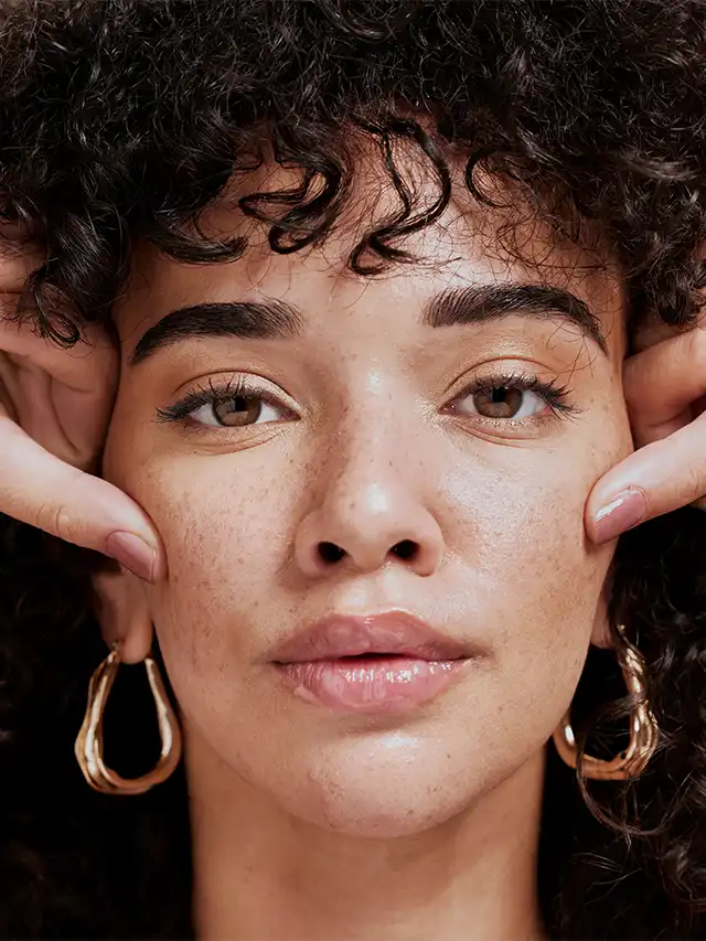 a woman with curly hair and earrings