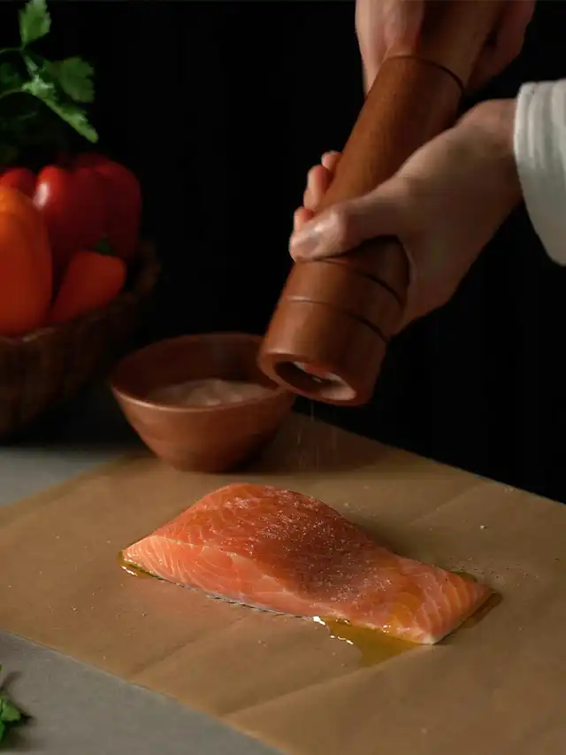 a person salting a piece of fish