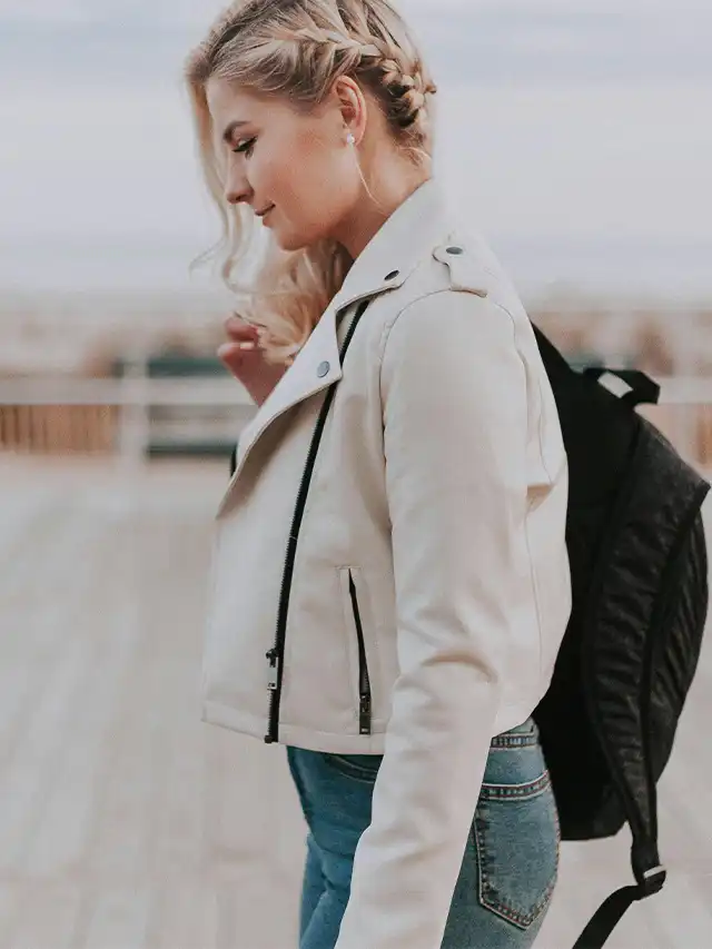 a woman wearing a white jacket and blue jeans