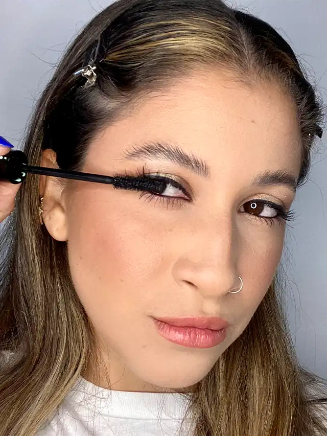 a woman applying mascara on her eyelashes