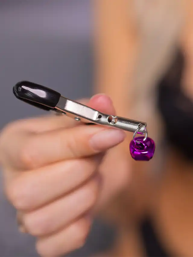 a hand holding a small metal object with a purple ball