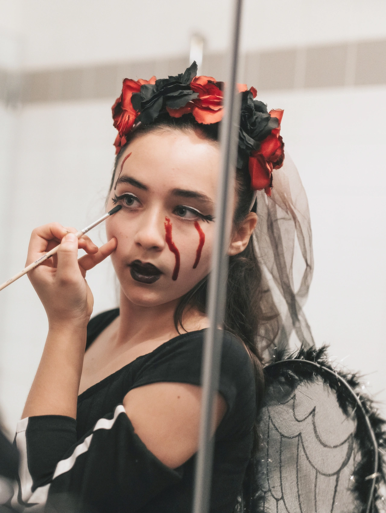 Maquillaje para Halloween con lágrimas de sangre y labios oscuros, ideal para un look espeluznante y elegante.