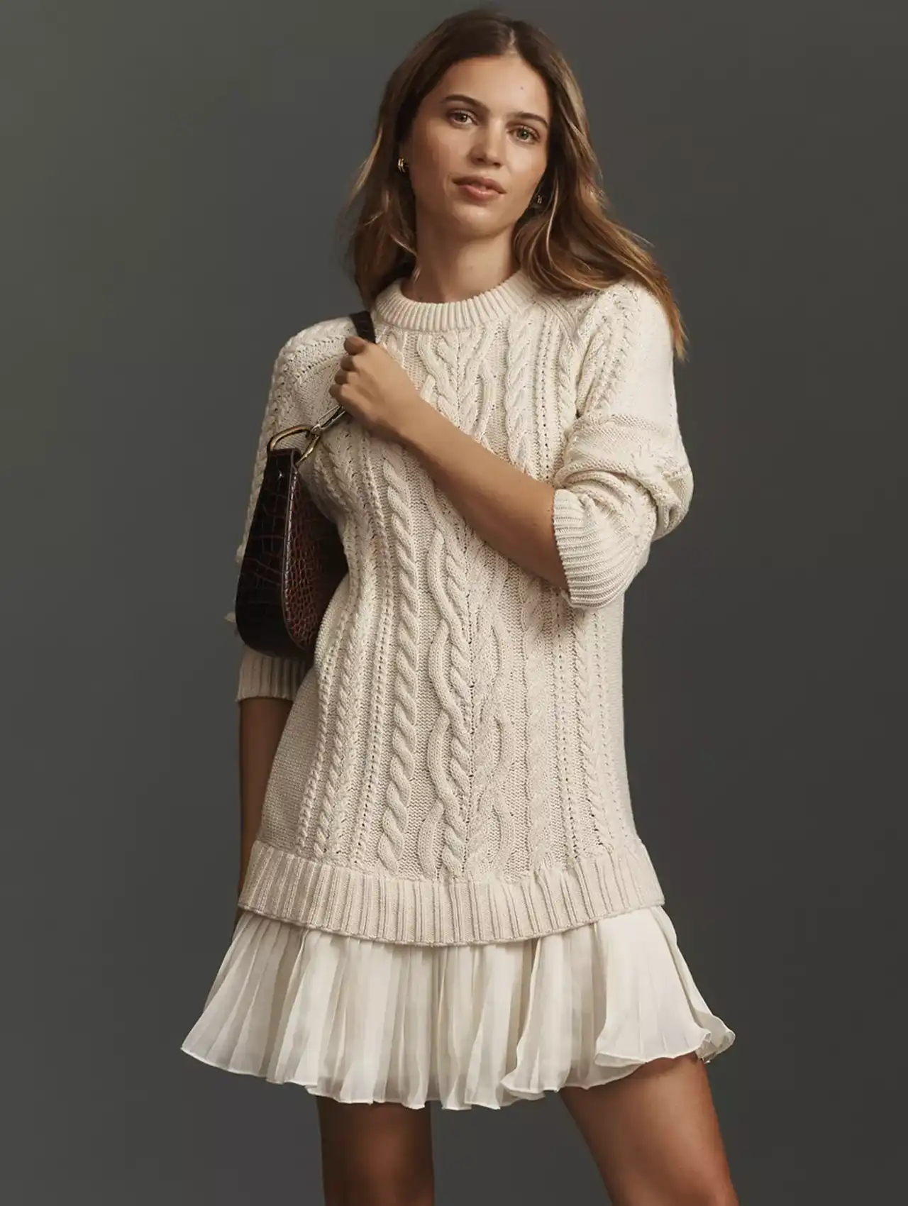 Woman in cream cable-knit sweater dress with pleated skirt hem, fall clothing for women