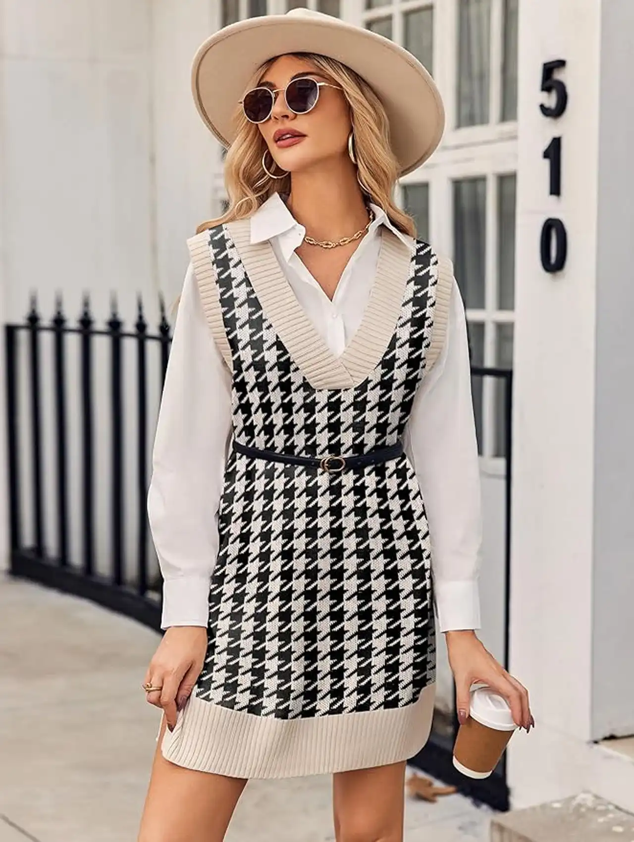 Woman wearing a houndstooth sweater vest mini dress layered over a white shirt with a hat, fall clothing for women