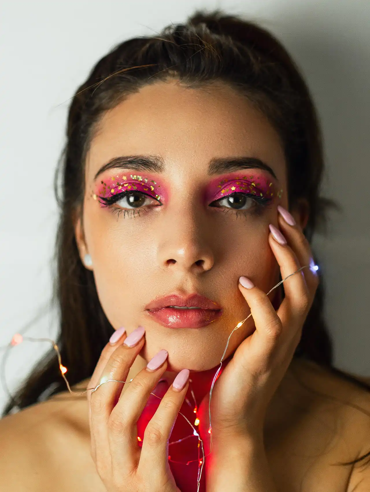 Maquillaje de ojos con sombras rosas y brillos decorativos