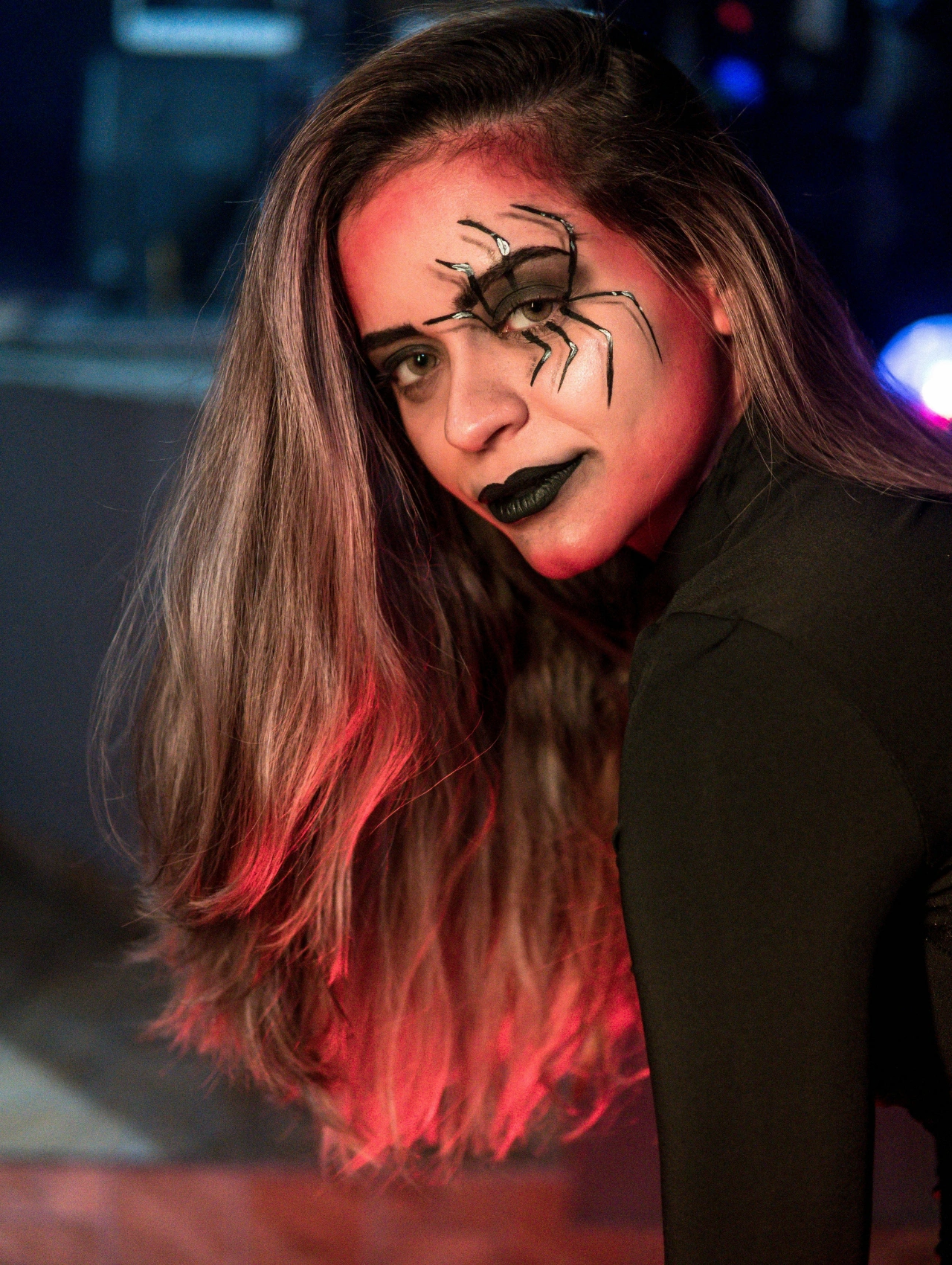 Maquillaje para Halloween con diseño de araña en el rostro y labios negros, estilo artístico y moderno.