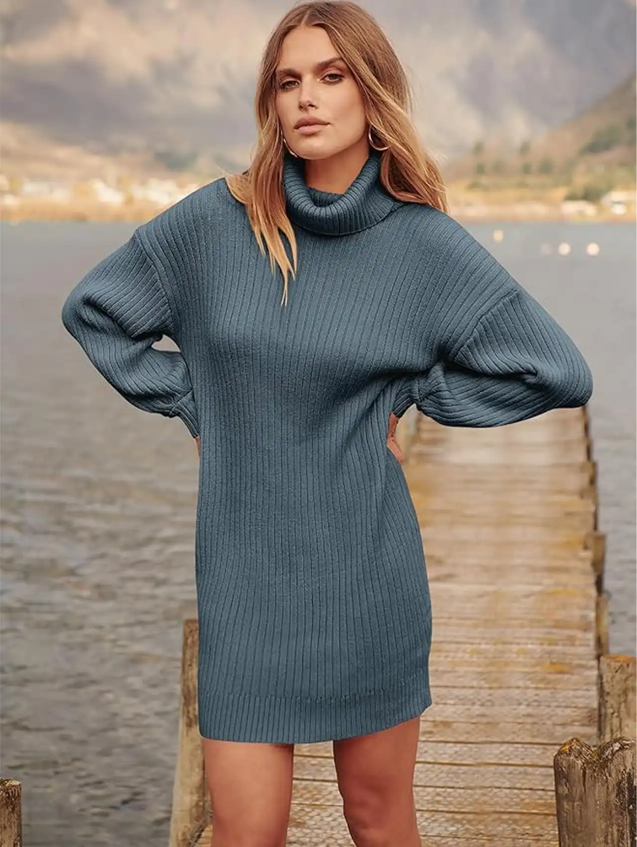 Woman in a blue oversized turtleneck sweater dress posing by the water, fall clothing for women