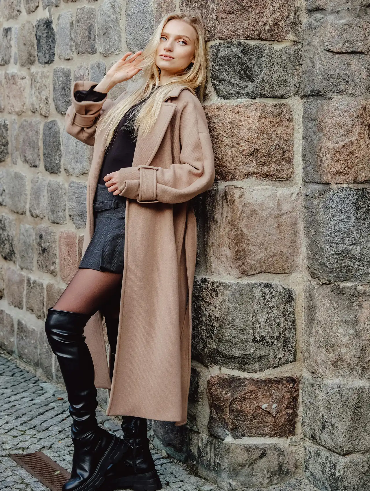 Woman wearing black best over-the-knee boots with a beige coat, styled for fall fashion.